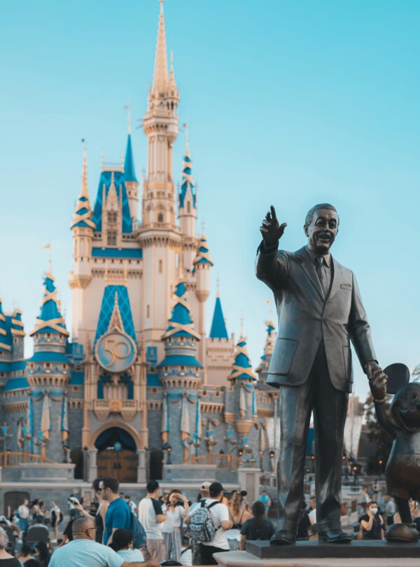 View of the iconic Cinderella Castle at Walt Disney World in Orlando, Florida, with crowd and statue.