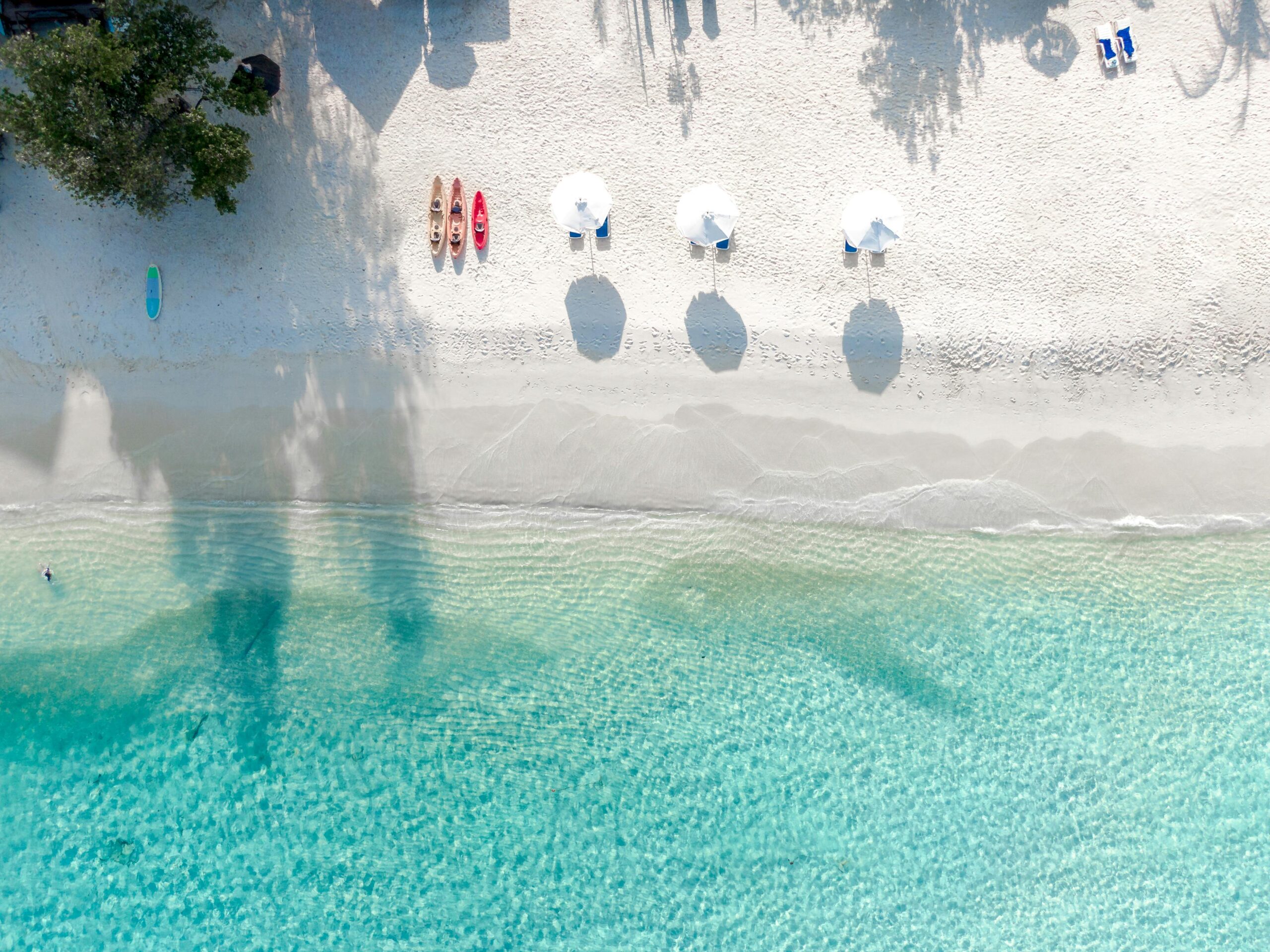 Stunning aerial view of a tropical beach with white sand and turquoise waters, perfect for a seaside escape.
