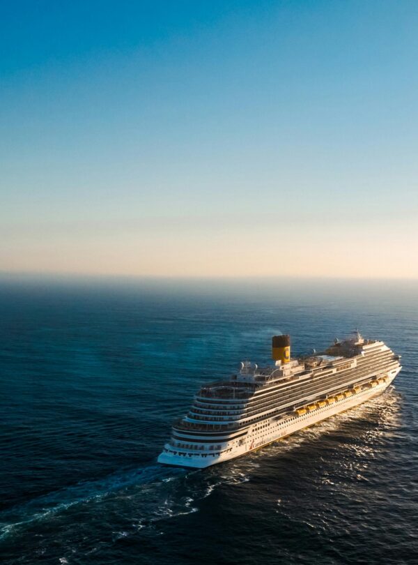 Aerial view of a luxury cruise ship navigating the calm ocean waters during sunset.
