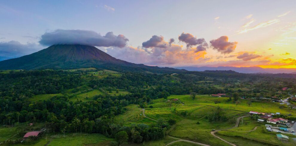 Breathtaking aerial view of Arenal Volcano at sunset in Alajuela Province, highlighting lush landscapes.