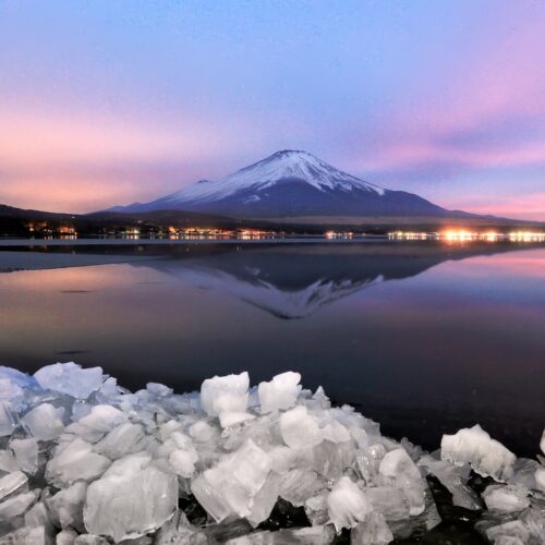 Captivating sunset over Mount Fuji reflected in a serene lake with icy foreground.