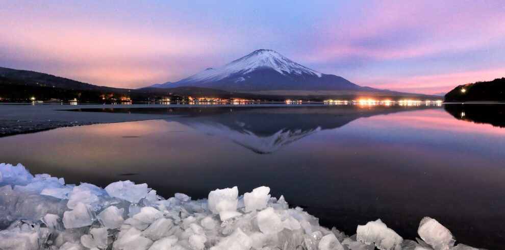 Captivating sunset over Mount Fuji reflected in a serene lake with icy foreground.